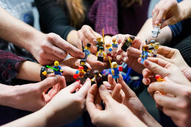 People holding miniature LEGO figures